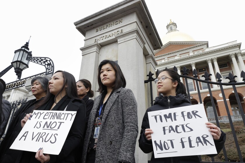 FILE- In this March 12, 2020 file photo, Jessica Wong, front left, Jenny Chiang, center, and Sheila Vo, from the state's Asian American Commission, stand together during a protest on the steps of the Statehouse in Boston. With a virtual event scheduled for Tuesday, May 4, 2021, Asian American business leaders in the United States are coming together to challenge discrimination against Asian Americans through a historical philanthropic donation. (AP Photo/Steven Senne, File)