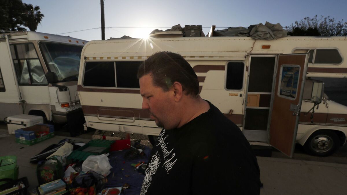 Vincent Neill sorts through personal belongings outside a motorhome parked in an industrial area of Chatsworth where he lives with his family.