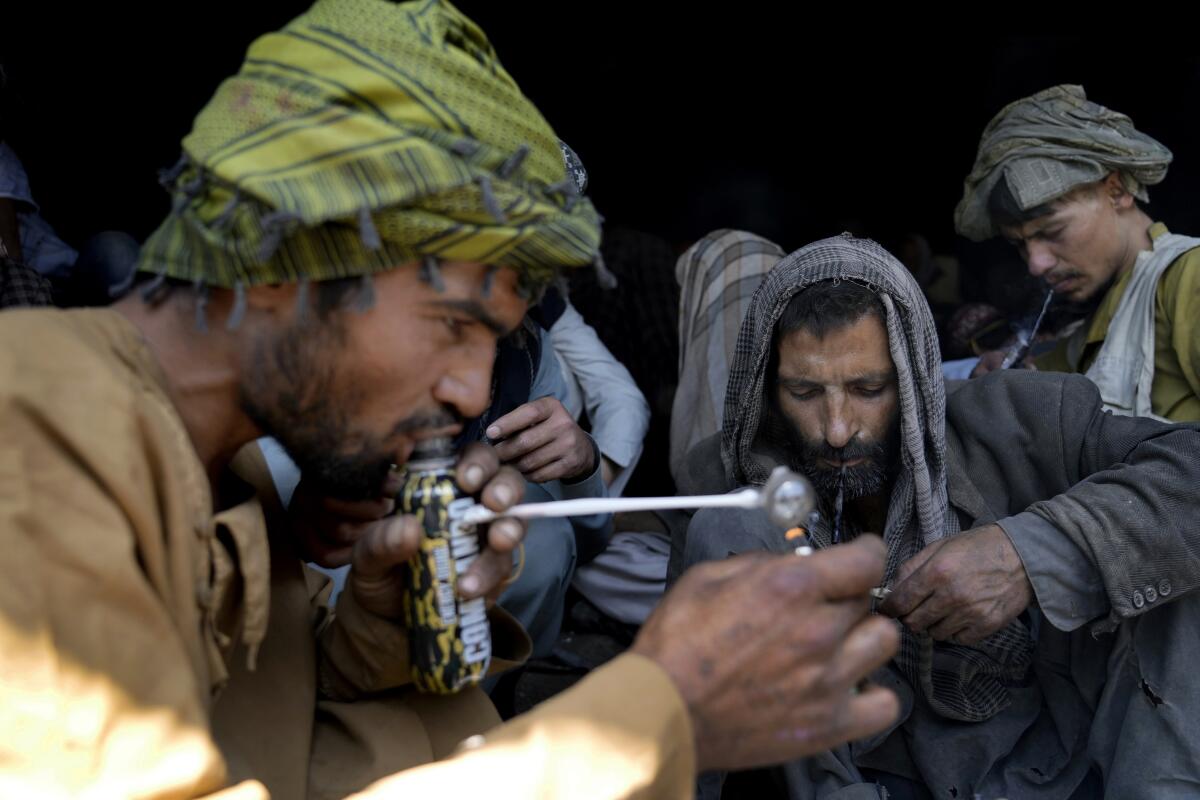 Addicts smoking heroin under a bridge in Kabul