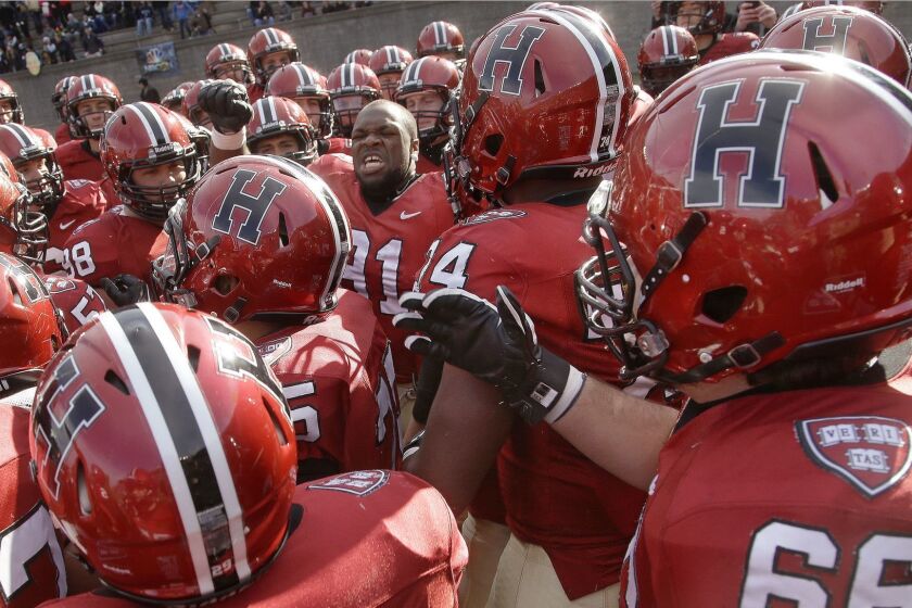 Members of the Harvard football team jump up and down as they prepare to take the field against their rivals Yale in an NCAA college football game at Harvard Stadium, Saturday, Nov. 22, 2014 in Cambridge, Mass. Harvard defeated Yale 31-24 to remain undefeated and win the Ivy League Championship. (AP Photo/Stephan Savoia)