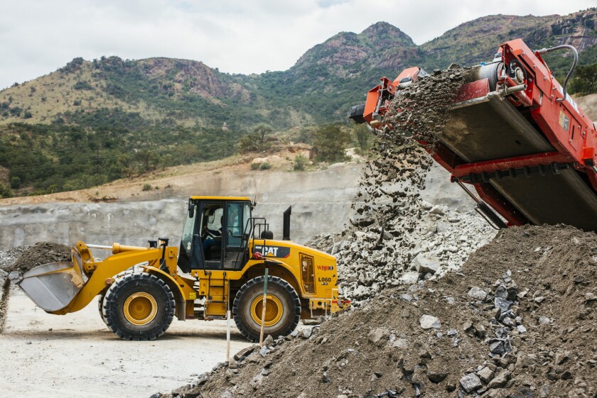 A conveyor deposits raw aluminum ore onto a stockpile as a Caterpillar Inc. excavator passes at the Northam Platinum Ltd. Booysendal platinum mine outside Lydenburg, South Africa, on Jan. 23, 2018.
