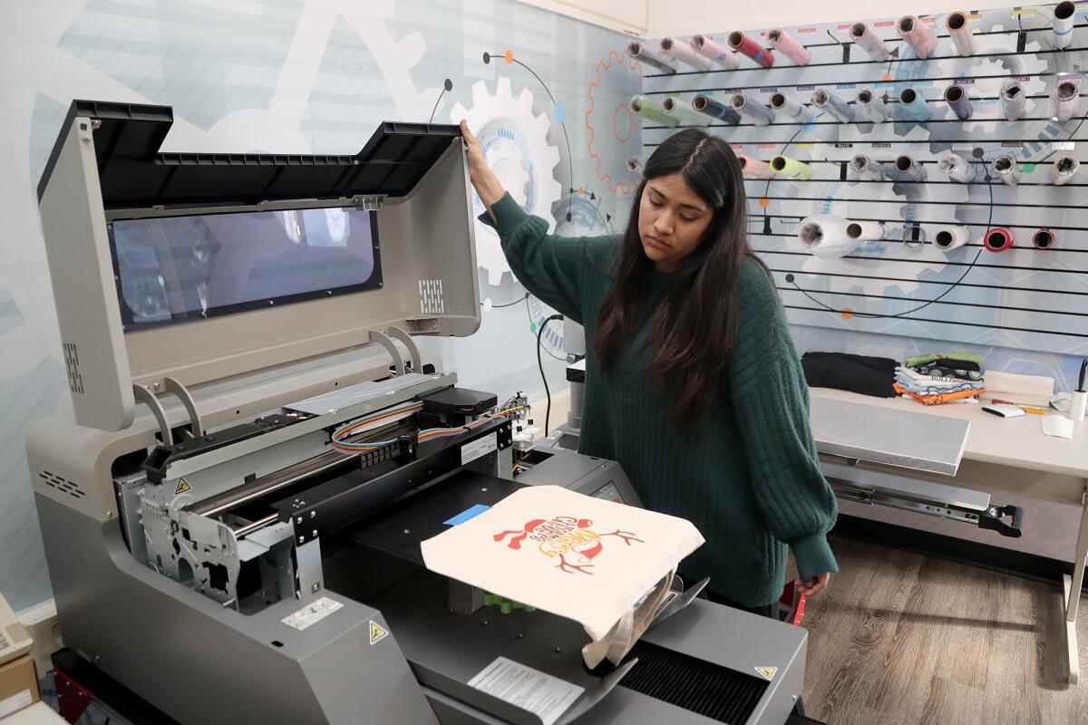 Lindsey Sanchez, 17, prints a "Merry Christmas" graphic design on a tote bag as a gift for a friend.