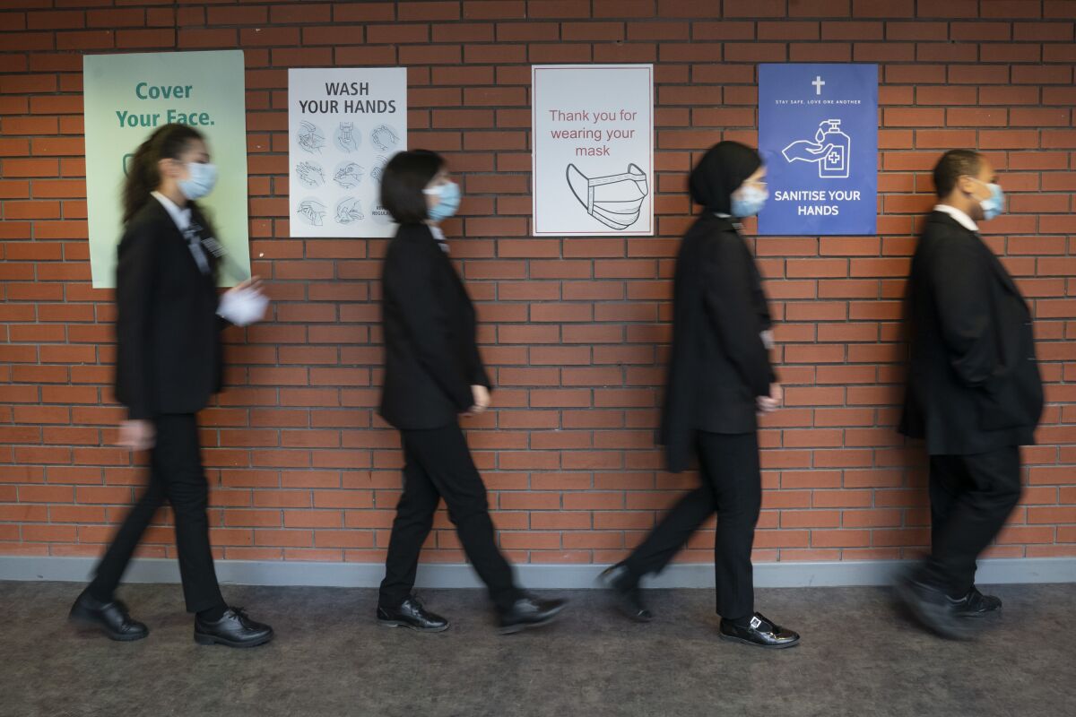 FILE - In this Monday, March 8, 2021 file photo, pupils queue for a socially distanced assembly at a school in in Manchester, England. The independent body advising the British government on the rollout of coronavirus vaccines says the direct health benefits of offering the jabs to all healthy 12 to 15 year olds are marginal. With just two per million of healthy children needing intensive care treatment for COVID-19, the Joint Committee on Vaccination and Immunisation said the “margin of benefit, based primarily on a health perspective, is considered too small to support advice on a universal program.” (Jon Super/PA via AP, File)