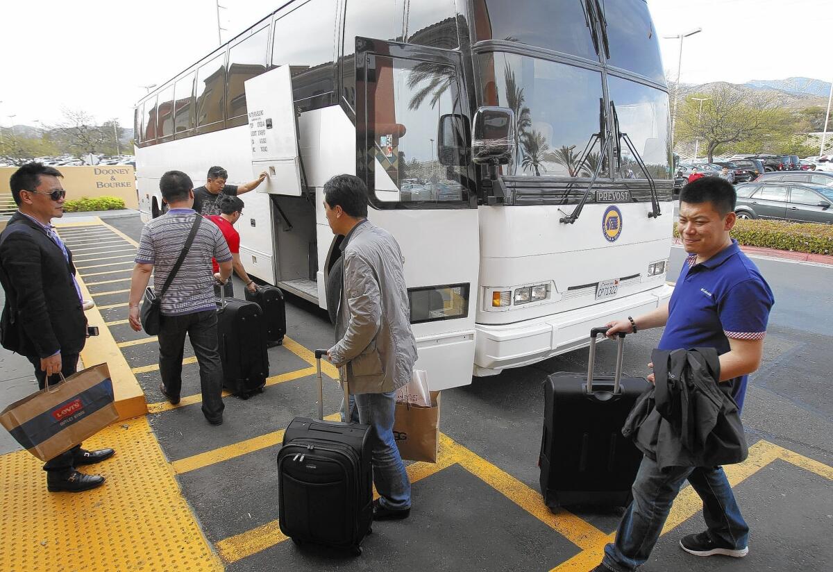 Chinese tourists board a bus with bags and suitcases of merchandise after shopping at the Desert Hills Premium Outlets in Cabazon in March 2013.