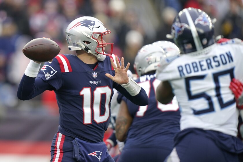 El quarterback de los Patriots de Nueva Inglaterra Mac Jones lanza el balón bajo presión 