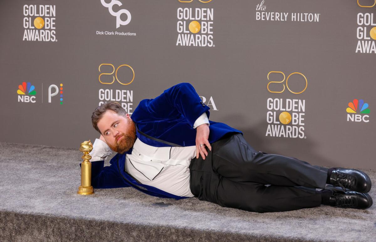 A man lays down with his Golden Globe award