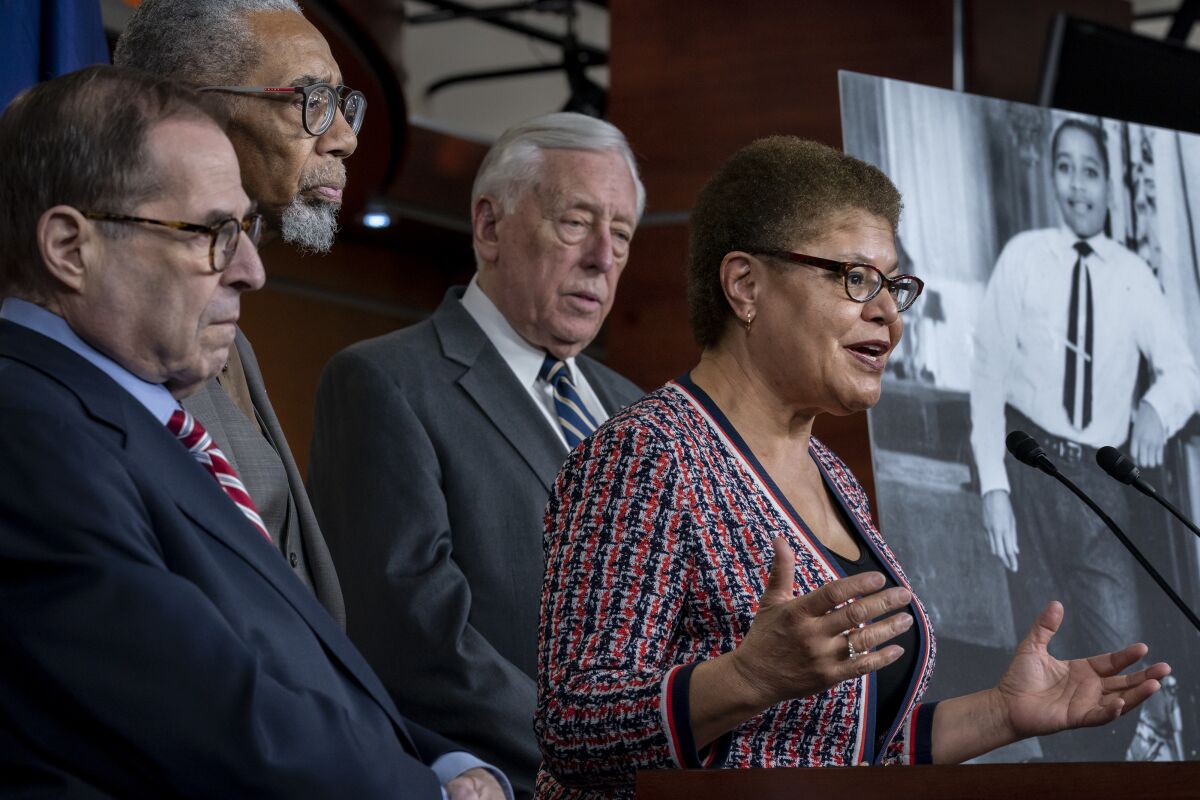 Rep. Karen Bass speaks at a lectern as other congressional lawmakers stand behind her