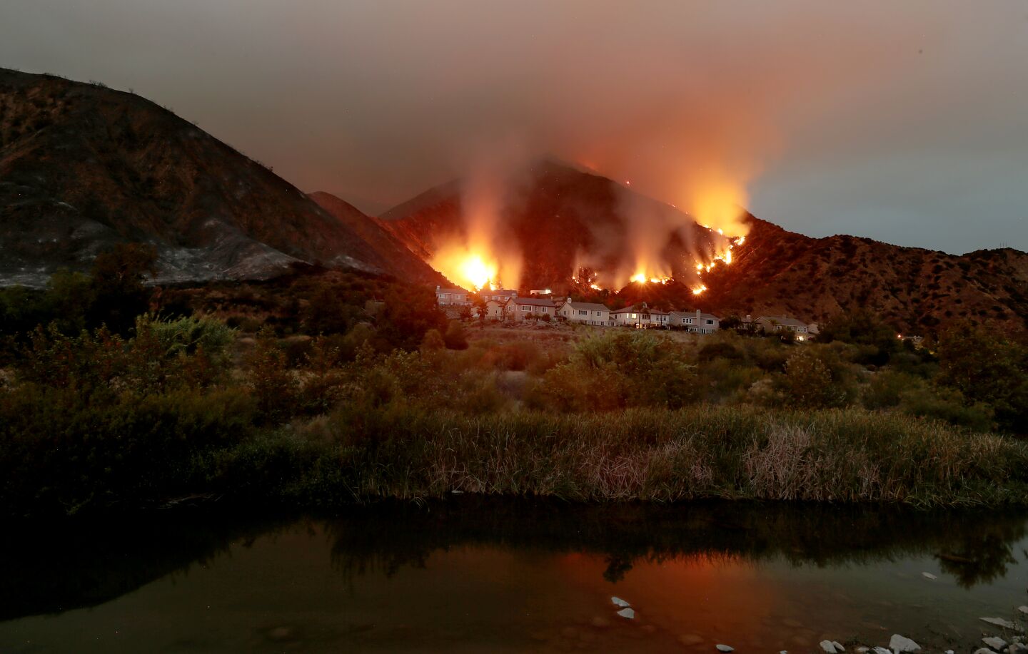 The Ranch fire burns in the hills above a cluster of homes along the San Gabriel River near Azusa on Thursday.