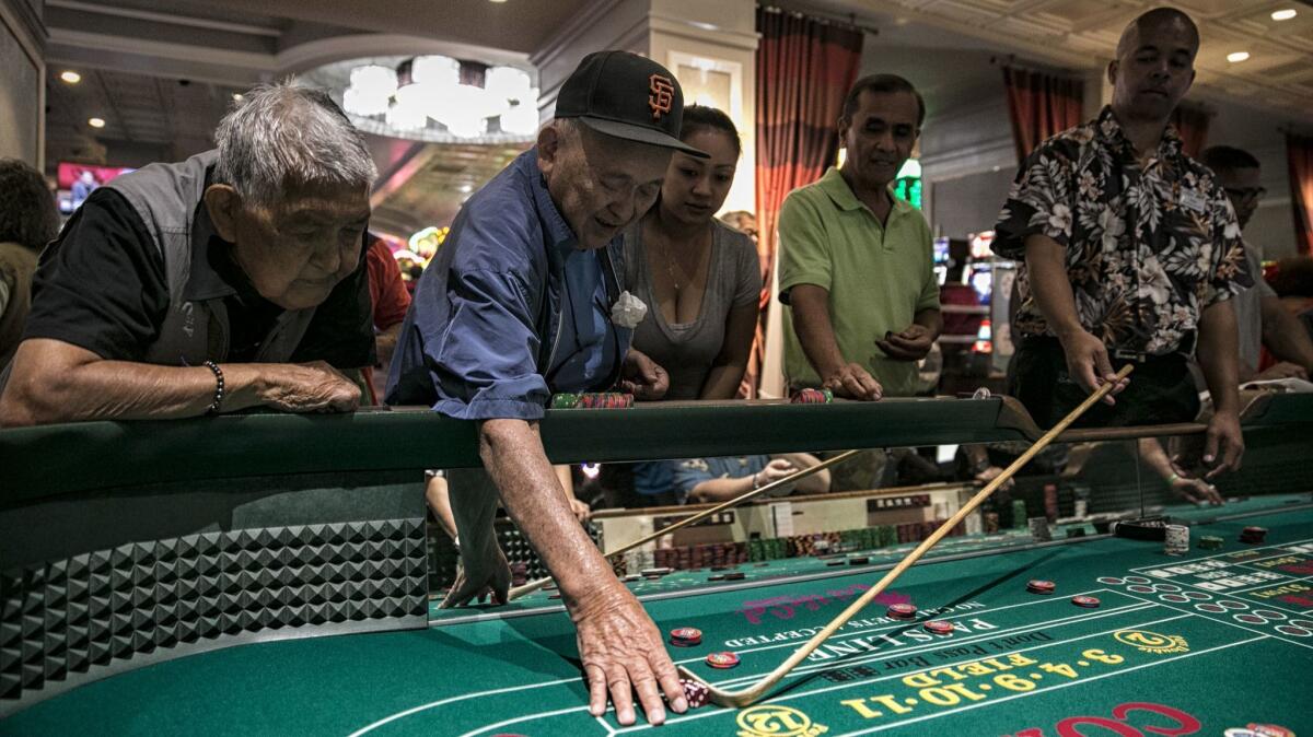 Masao Yamamoto, 82 and blind, reaches for dice during a successful series of rolls at the California Casino Golden Arm Craps Tournament.