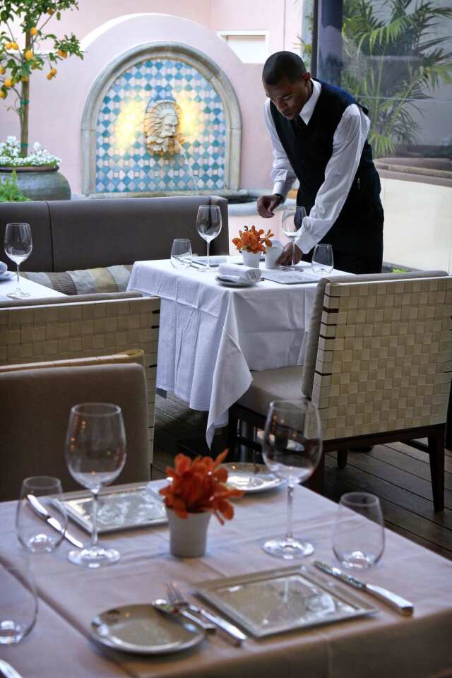 Waiter Marcus Williamson sets tables on the patio.