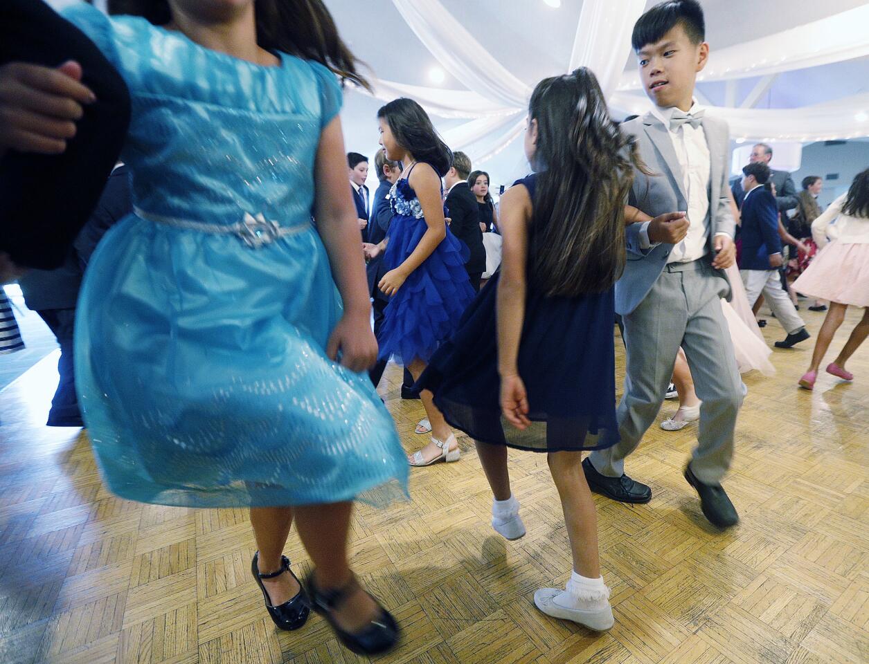 Sofi Aslanian, 9, of La Canada Flintridge, dances with Caden Ho, 10, of La Canada Flintridge as they learn the Mexican Hat Dance at the first basic introductory class of a basic etiquette class taught by Gollatz Cotillion at the La Canada Flintridge Country Club on Tuesday, September 25, 2018. Fourth-graders, where the boys must wear ties and the girls wear dresses, were instructed in the art of conversation, making eye contact, the handshake, basic dining skills and dancing with a partner.
