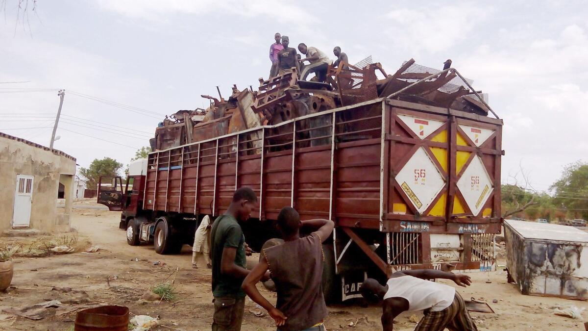 Residents evacuate in a truck full of metal sheets collected from houses burned after Boko Haram attacks in Buni Yadi on May 21, 2016.