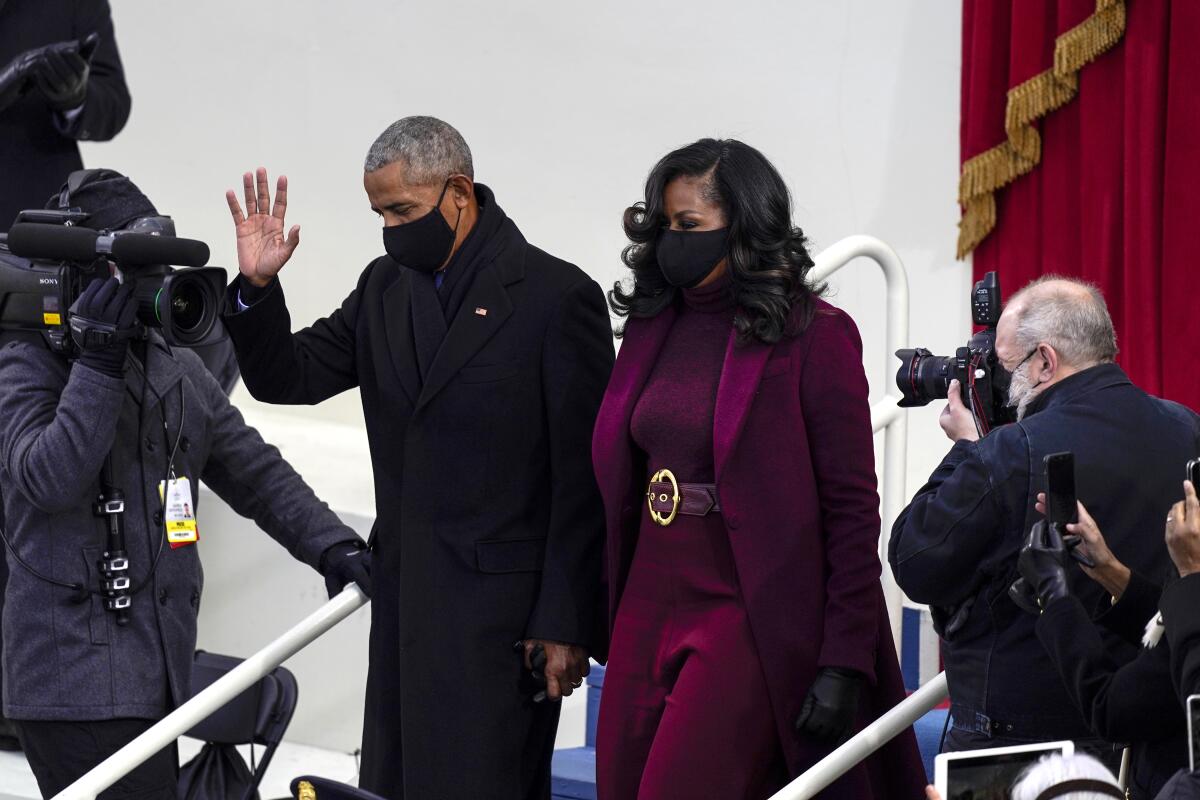 Barack Obama and Michelle Obama walk next to photographers