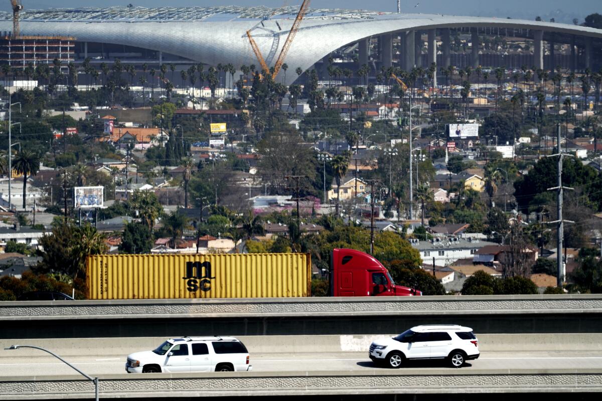 Freeway traffic passes Inglewood, with SoFi Stadium in the background.