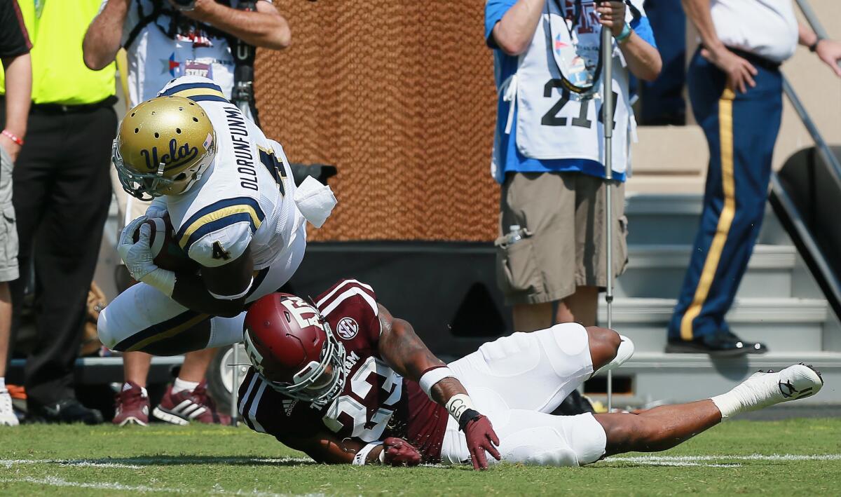 UCLA running back Bolu Olorunfunmi is knocked out of bounds by Texas A&M defensive back Armani Watts during the season opener.