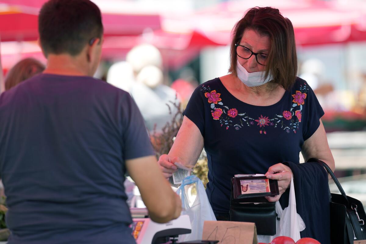 A customer pays using Croatian Kunas at the vegetable market in downtown Zagreb, Croatia, Tuesday, July 12, 2022. The European Union is set to remove the final obstacles for Croatia to adopt the euro, ensuring the first expansion of the currency bloc in almost a decade. (AP Photo/Darko Bandic)