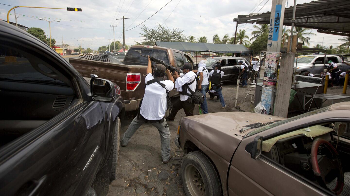 Men belonging to the Self-Defense Council of Michoacan engage in a firefight while trying to flush out alleged members of the Knights Templar drug cartel from Nueva Italia, Mexico on Jan. 12, 2014. The vigilantes said they were liberating territory. Mexican troops and police stayed away.