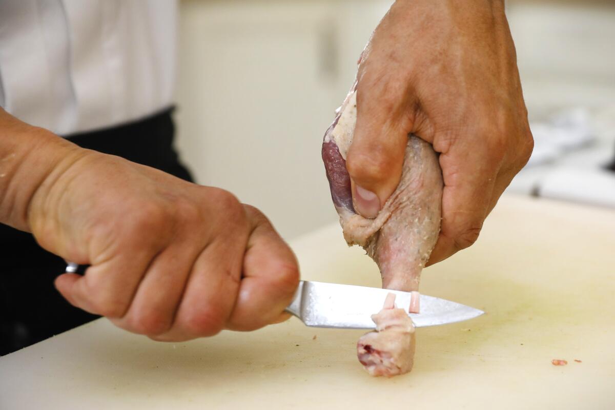 Frenching the duck leg, for a cleaner presentation, involves removing the meat and other tissues from the top of the bone.