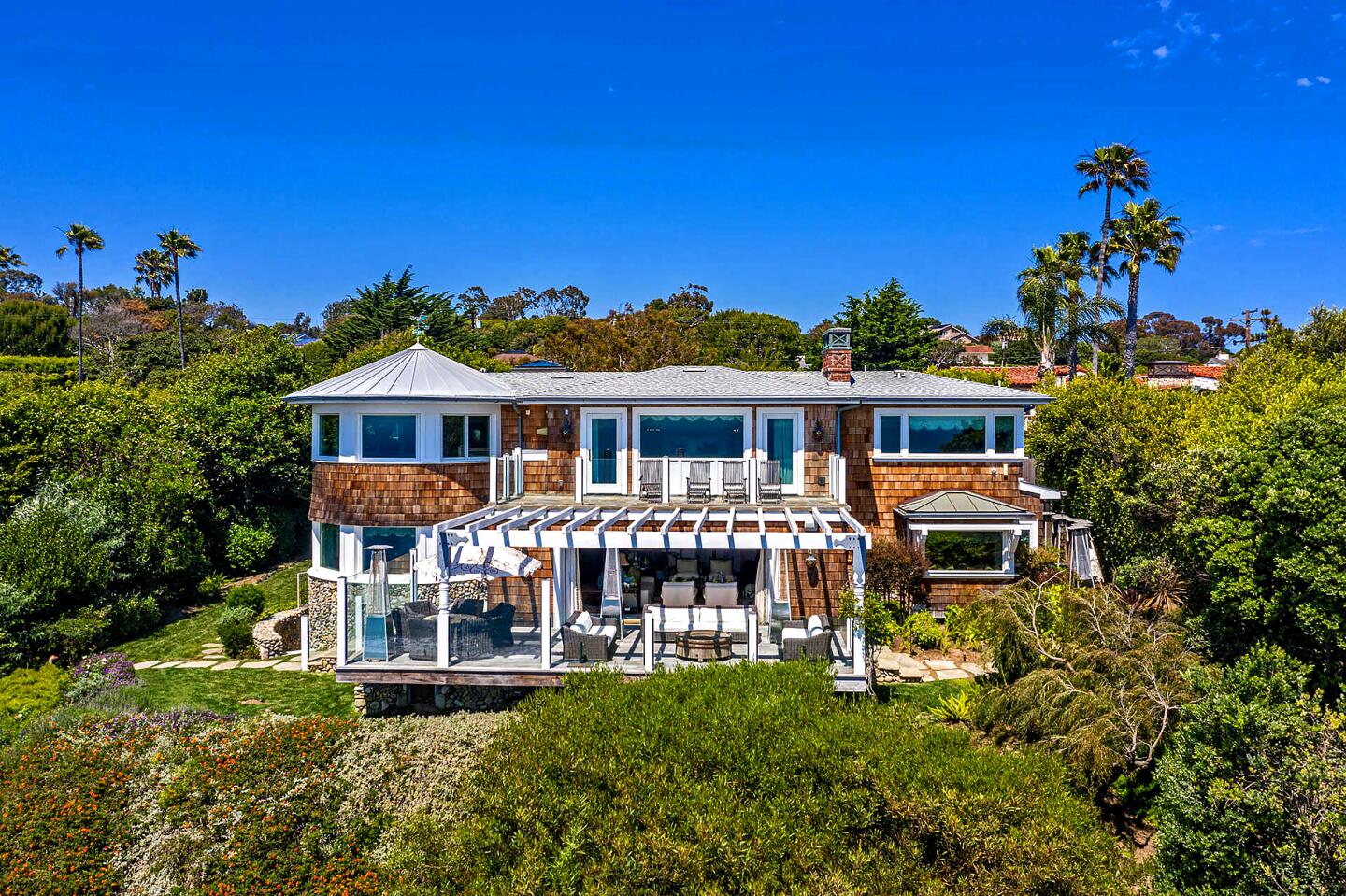 This coastal Cape Cod overlooks the ocean from a bluff in Point Dume, descending to a stretch of private beach.