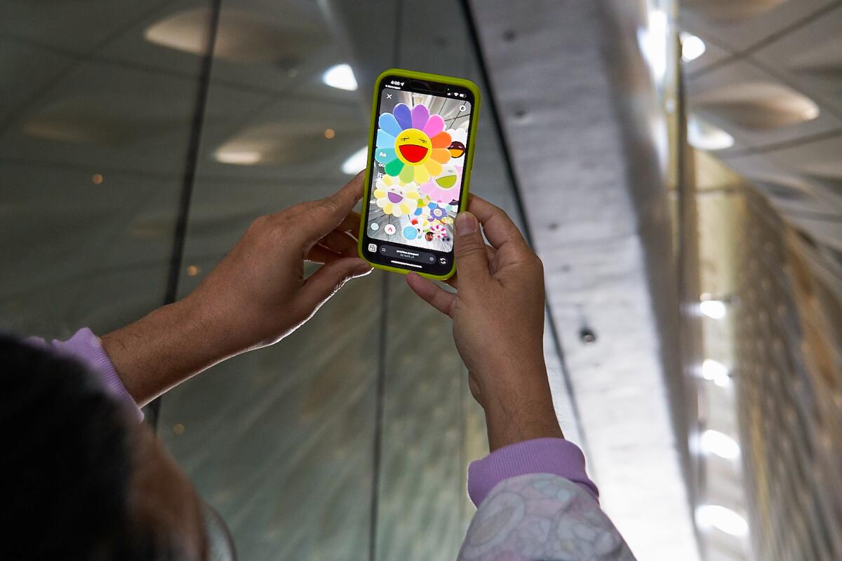 A person holds up their cellphone, which shows colorful images.