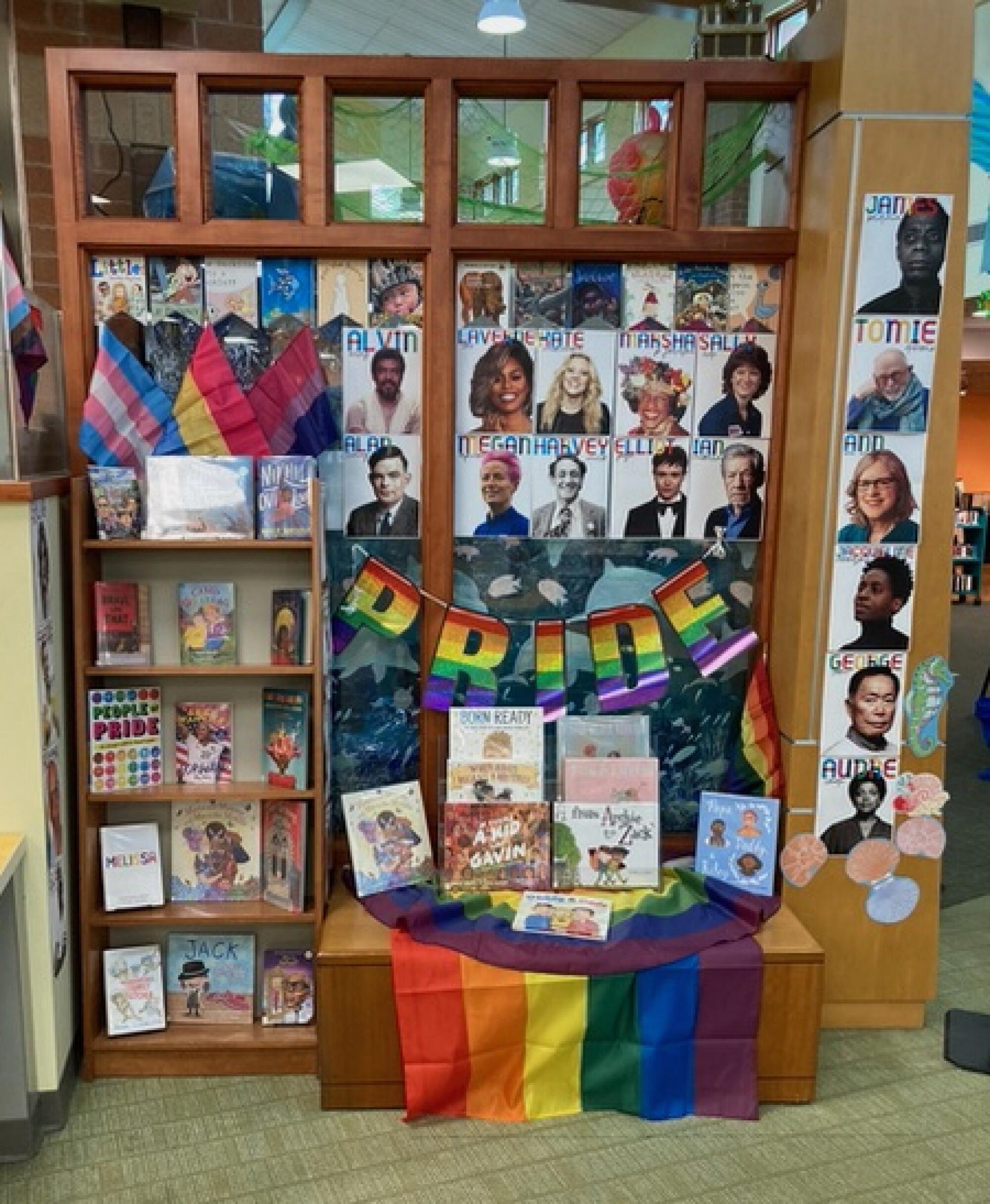 A display of LGBTQ Pride flags and photos in a library