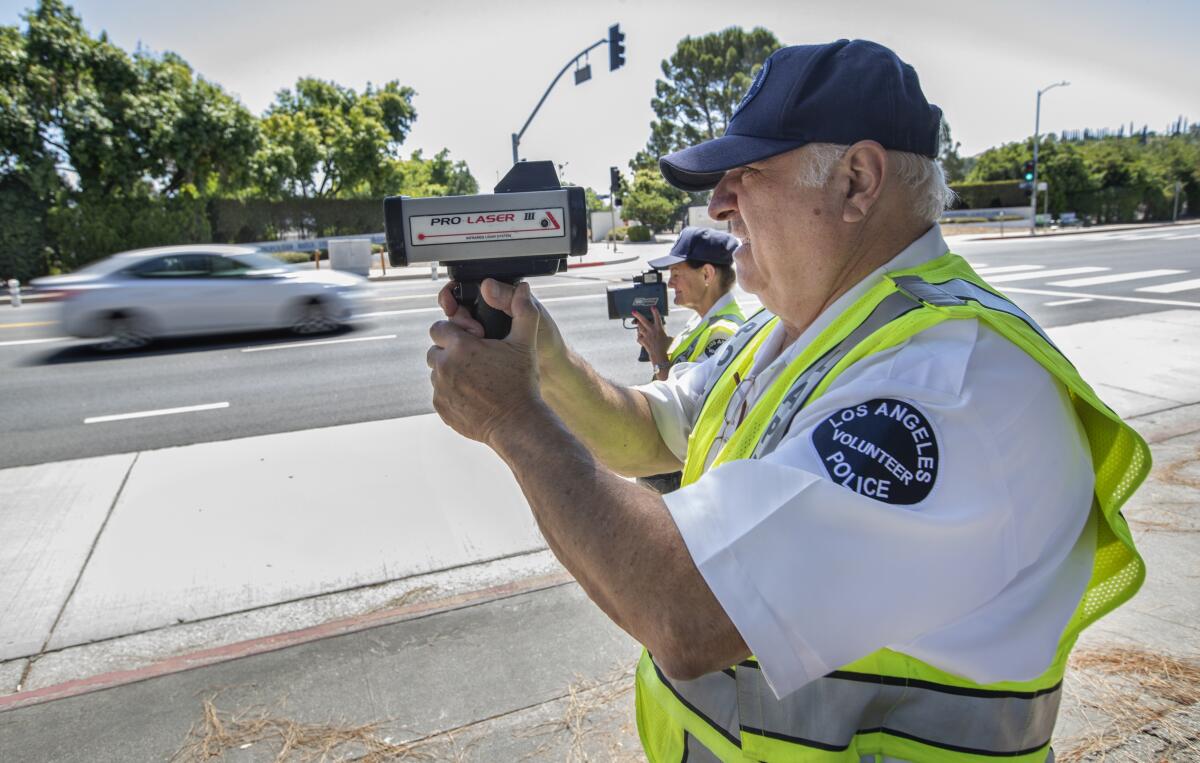 Police volunteers Karla Hanley, left, and Nishan Darakdjian use radar guns in 2019 to catch speeders on Balboa Boulevard.