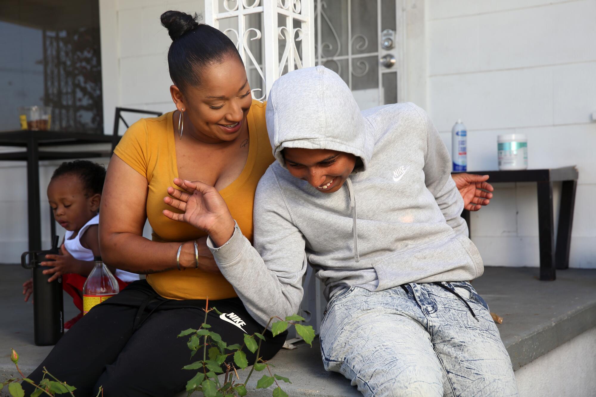 A woman plays on the porch of her South L.A. home with two of her children