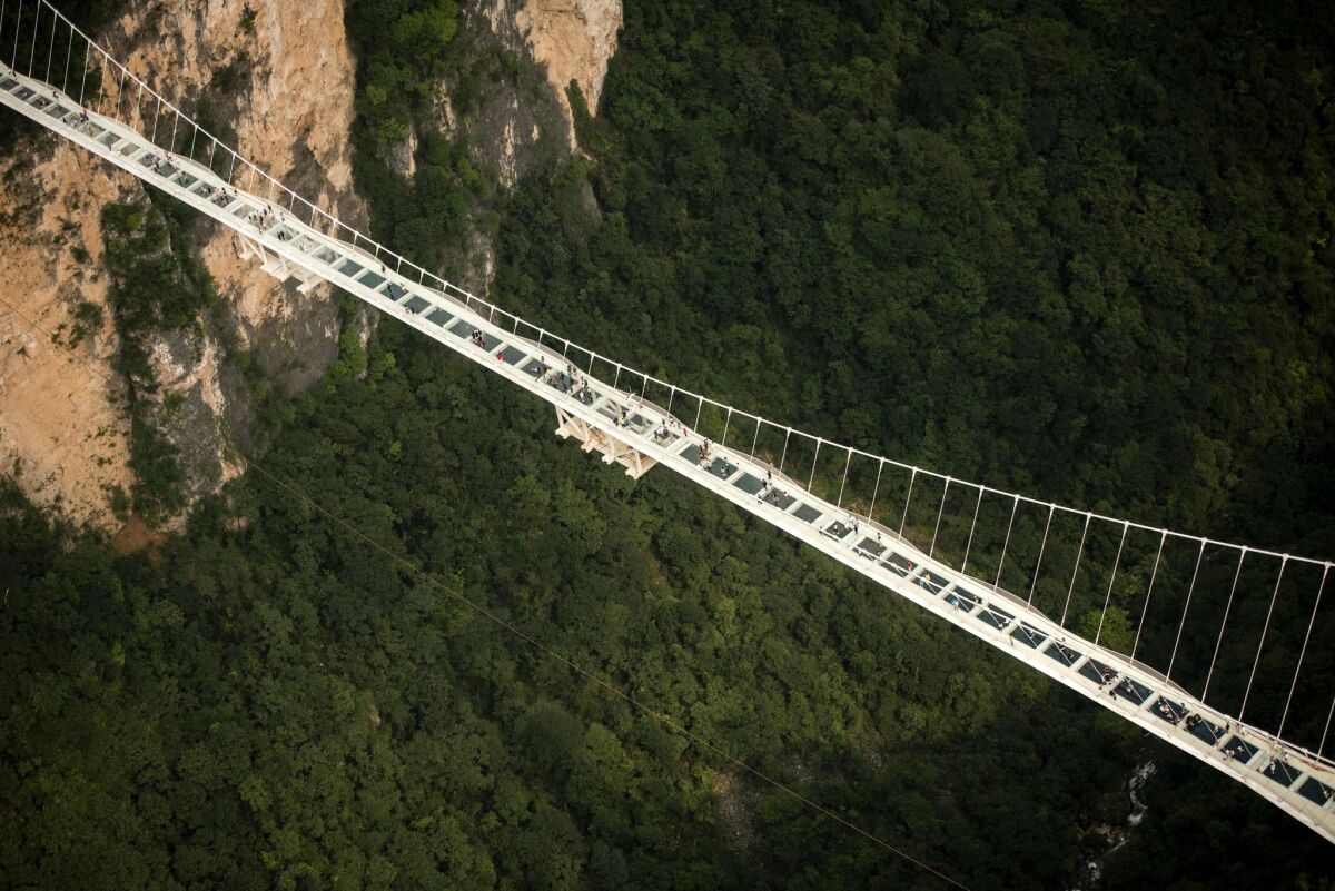 The bridge allows visitors to cross over a lush canyon in a forested part of China's Hunan province.