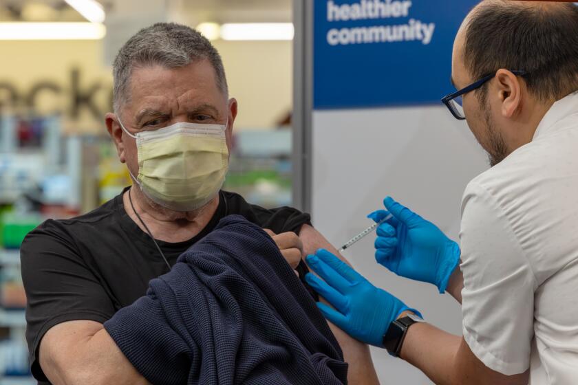 EAGLE ROCK, CA - SEPTEMBER 14: Pharmacist Aaron Sun administers new vaccine COMIRNATY? (COVID-19 Vaccine, mRNA) by Pfizer, to John Vuich at CVS Pharmacy in Eagle Rock, CA. (Irfan Khan / Los Angeles Times)