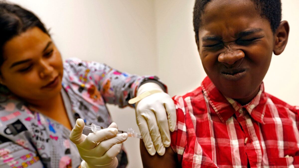 Desmond Sewell, 12, receives his vaccinations by medical assistant Jessica Reyes at the Lou Colen Children's Health and Wellness Center in Mar Vista.