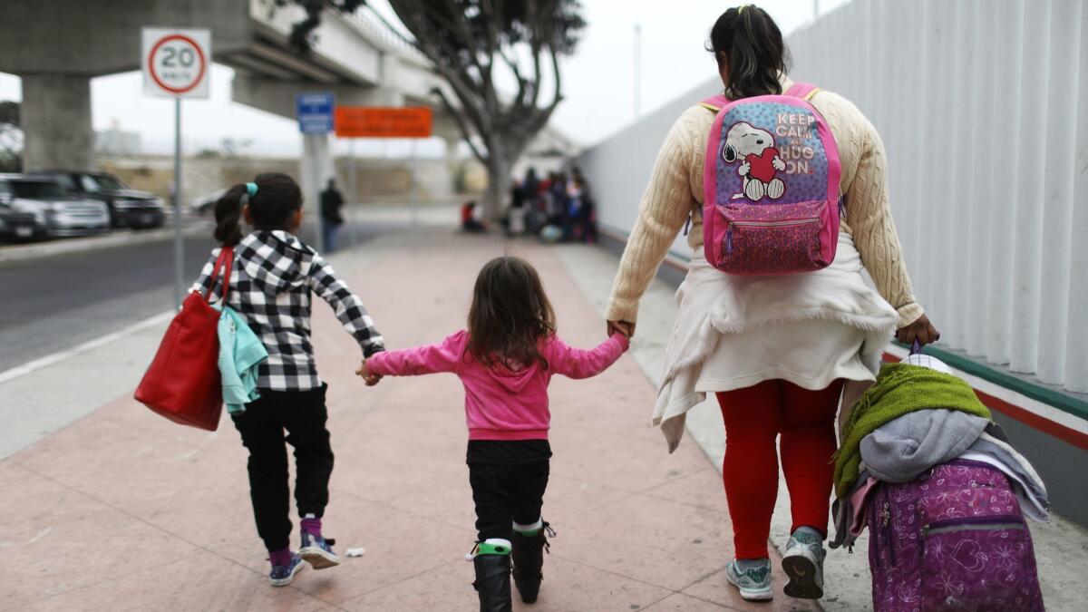 A migrant mother seeking asylum in the U.S. walks with her two daughters and their belongings on their way to the port of entry in Tijuana on June 21.