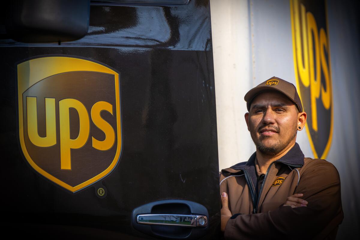 A UPS truck driver stands in front of his truck