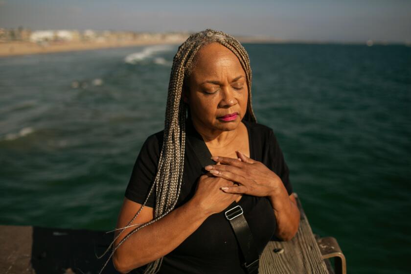 Los Angeles, CA - June 03: With her hands clasped over her heart, Deneen Vaughn takes a moment to reflect on her son Chris who died by suicide on Saturday, June 3, 2023 in Los Angeles, CA. Vaughn stands on the Venice Beach pier at the location where she and her family released the ashes their loved one. (Jason Armond / Los Angeles Times)