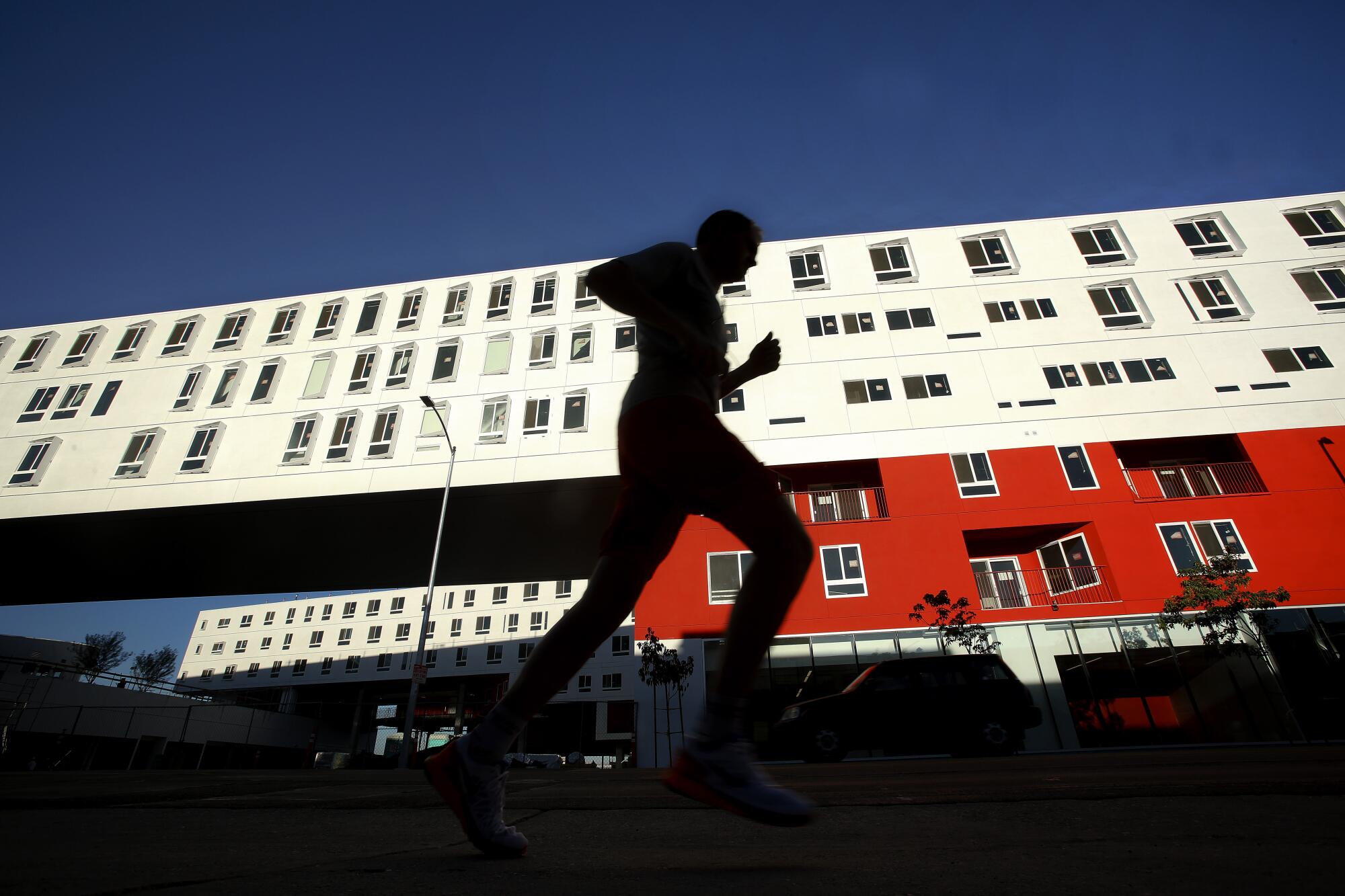 A jogger passes a red and white building.