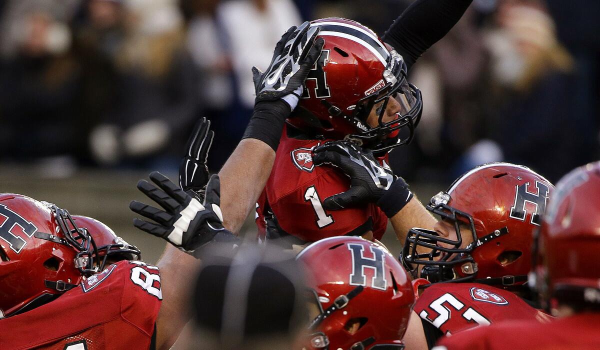 Harvard wide receiver Andrew Fischer (1) is lifted by teammates after he scored the go-ahead touchdown late in the fourth quarter against Yale on Saturday.