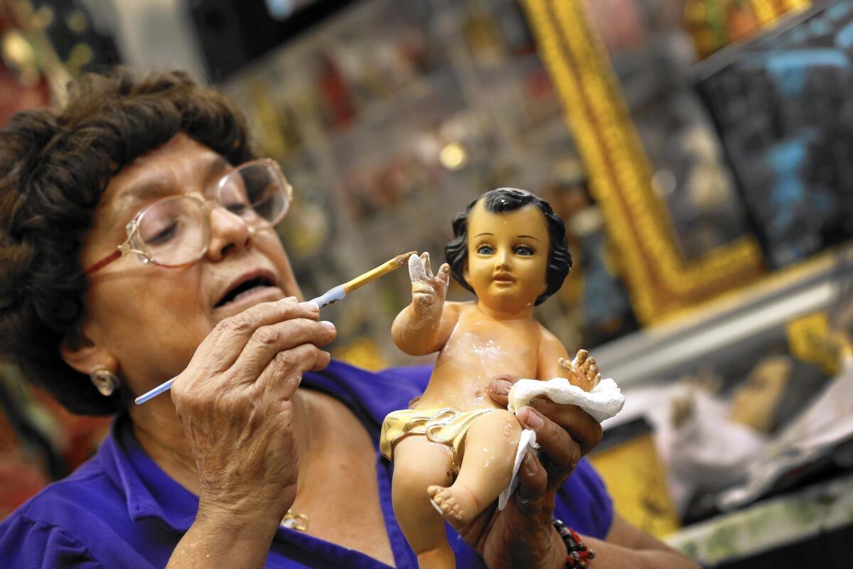 Christina Parodi repairs the finger of a baby Jesus that had been chewed by a dog.
