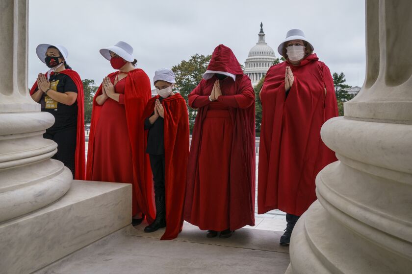 Activists opposed to the confirmation of President Donald Trump's Supreme Court nominee, Judge Amy Coney Barrett, are dressed as characters from "The Handmaid's Tale," at the Supreme Court on Capitol Hill in Washington, Sunday, Oct. 11, 2020. Barrett's confirmation hearing begins Monday before the Republican-led Senate Judiciary Committee. (AP Photo/J. Scott Applewhite)