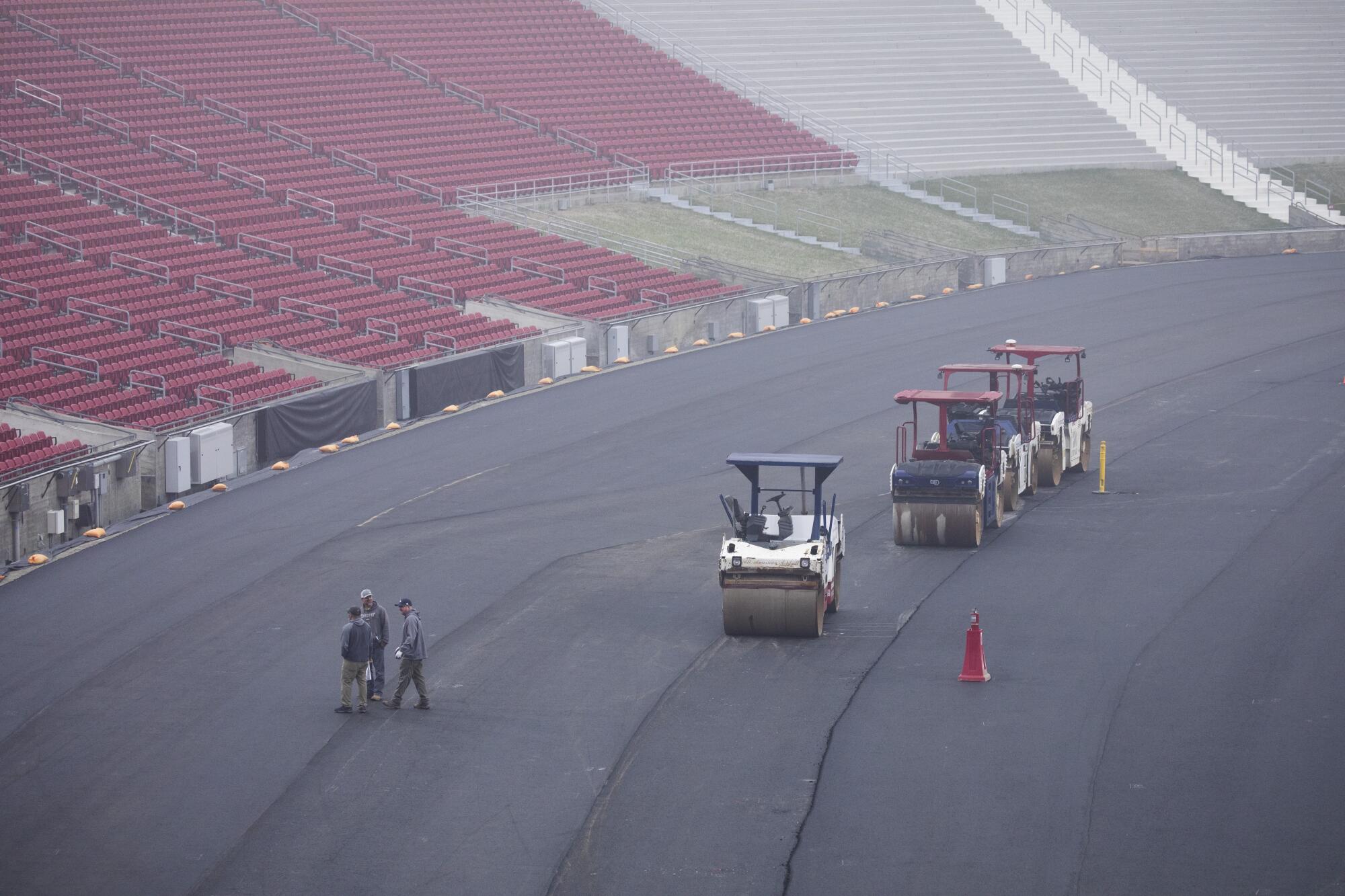 Construction workers steamroll asphalt inside the Coliseum in preparation for a NASCAR exhibition race.