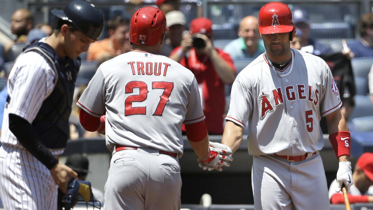 Angels center fielder Mike Trout (27) is greeted by designated hitter Albert Pujols after hitting a solo home run against the Yankees in the first inning Sunday. Pujols would follow with another.