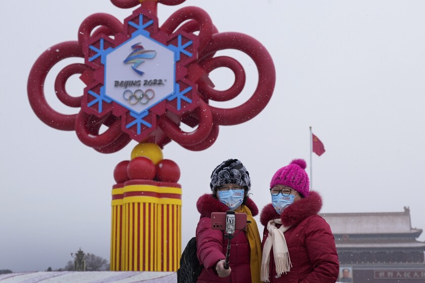 Dos mujeres, con mascarillas con el eslogan de los JJOO de Invierno de Beijing