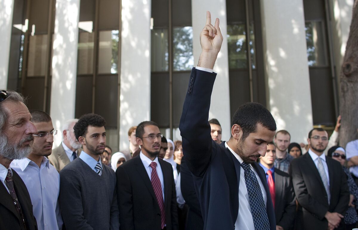 With his co-defendants standing behind, Muslim student Mohamed Mohy-Eldeen Abdelgany holds up a peace sign while speaking after he and the others were found guilty of disrupting a speech by the Israeli ambassador at UC Irvine.