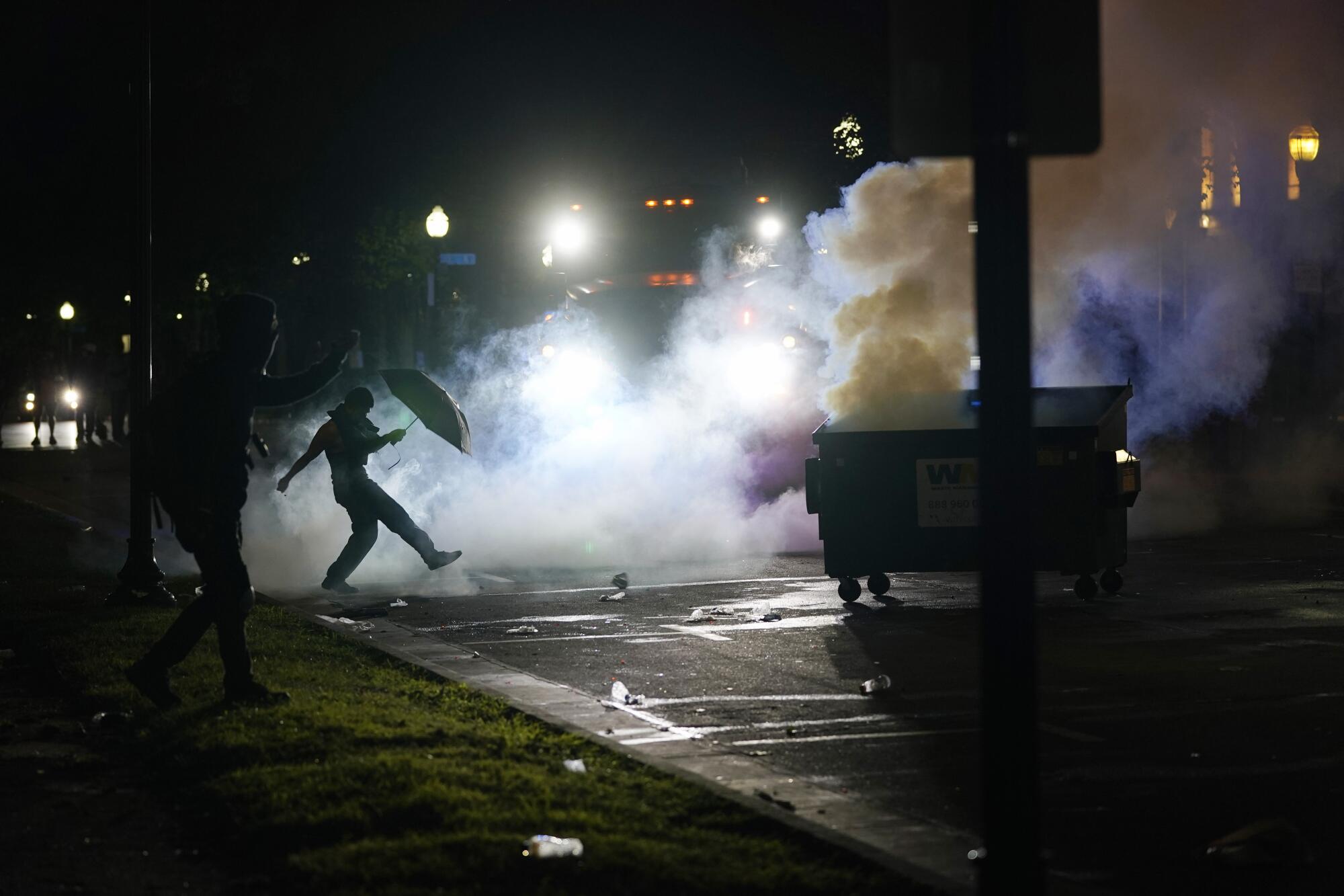 A protester kicks a smoke canister 