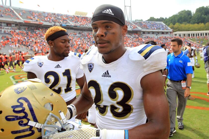 UCLA running back Nate Starks, No. 23, and defensive back Tahaan Goodman, No. 21, walk off the field after the Bruins' 28-20 win over Virginia on Saturday at Scott Stadium in Charlottesville, Va.