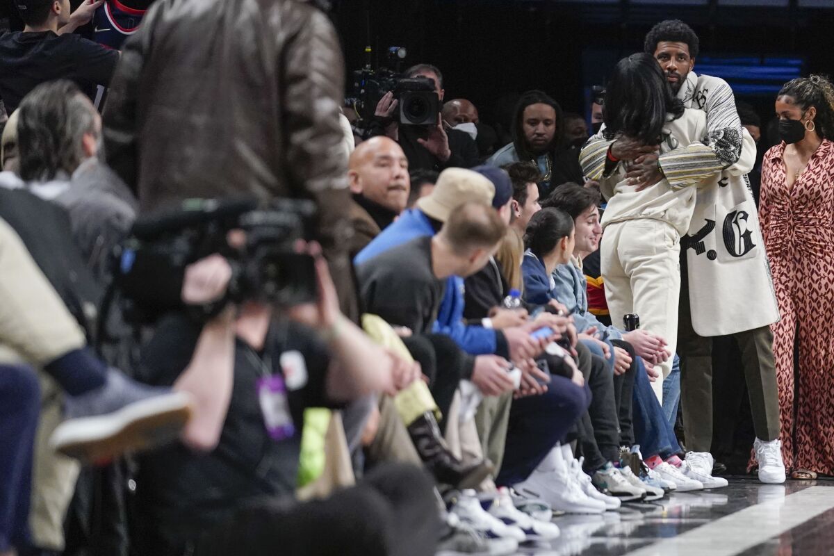 Brooklyn Nets' Kyrie Irving, right, greets people as he enters the arena during the first half of the NBA basketball game between the Brooklyn Nets and the New York Knicks at the Barclays Center, Sunday, Mar. 13, 2022, in New York. (AP Photo/Seth Wenig)