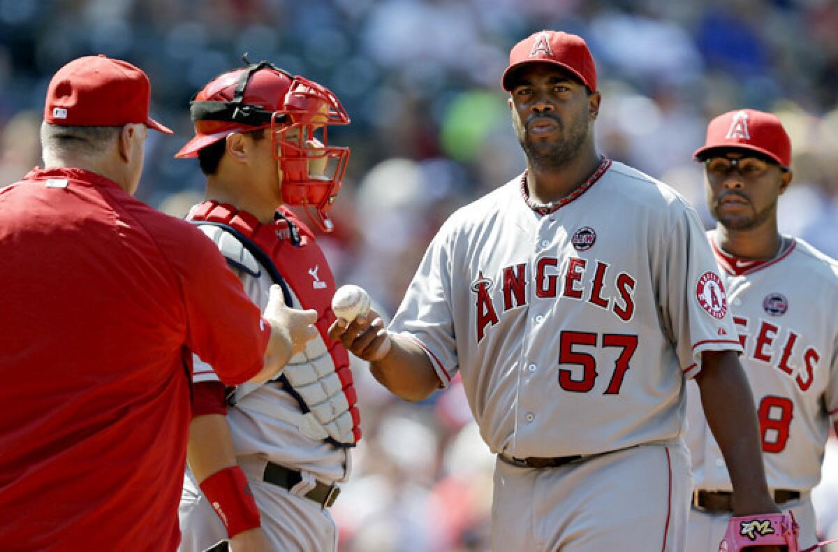 Angels starting pitcher Jerome Williams hands the ball to Manager Mike Scioscia after getting knocked out of the game in the sixth inning against the Indians on Sunday in Cleveland.