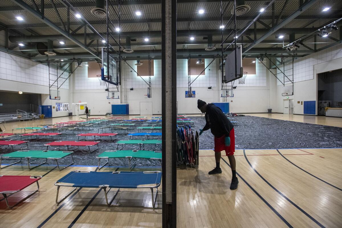 L.A. parks and recreation staffer Chris Smith helps set up cots at Westwood Recreation Center in March