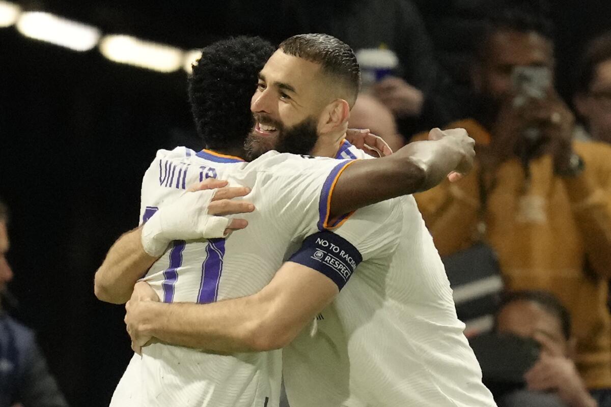 Real Madrid's Karim Benzema, right, celebrates with his teammate Real Madrid's Vinicius Junior after scoring his side's third goal during a Champions League first-leg quarterfinal soccer match between Chelsea and Real Madrid at Stamford Bridge stadium in London, Wednesday, April 6, 2022. (AP Photo/Kirsty Wigglesworth)