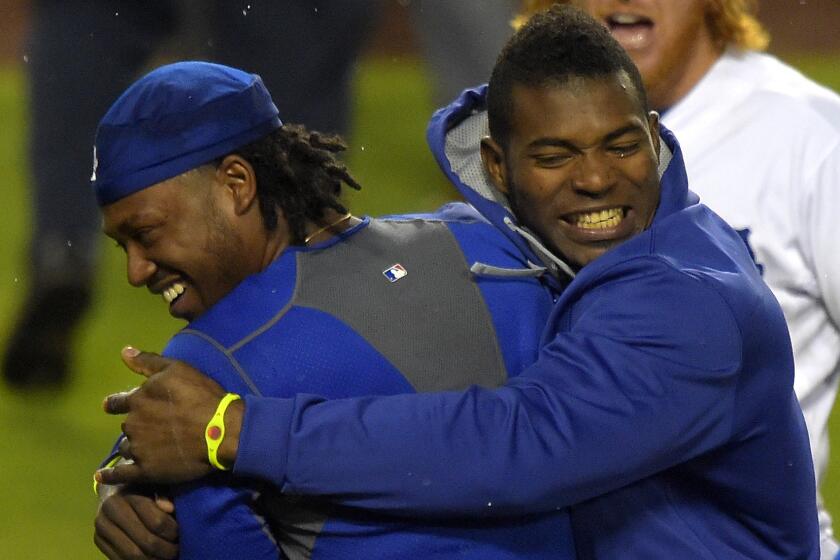 Dodgers shortstop Hanley Ramirez, left, is hugged by teammate Yasiel Puig after hitting a walk-off home run during the 12th inning of the team's 5-2 win over the Chicago Cubs on Saturday.