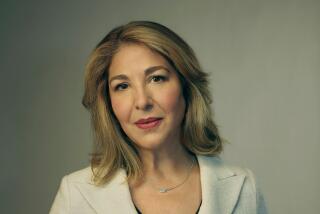 A woman with sandy blond hair stands in a white jacket over a black dress shirt.