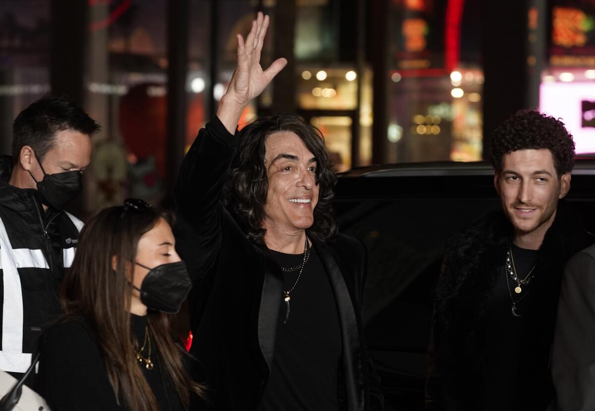 A man with long hair waves to the crowd as he arrives at a Hollywood movie premiere.